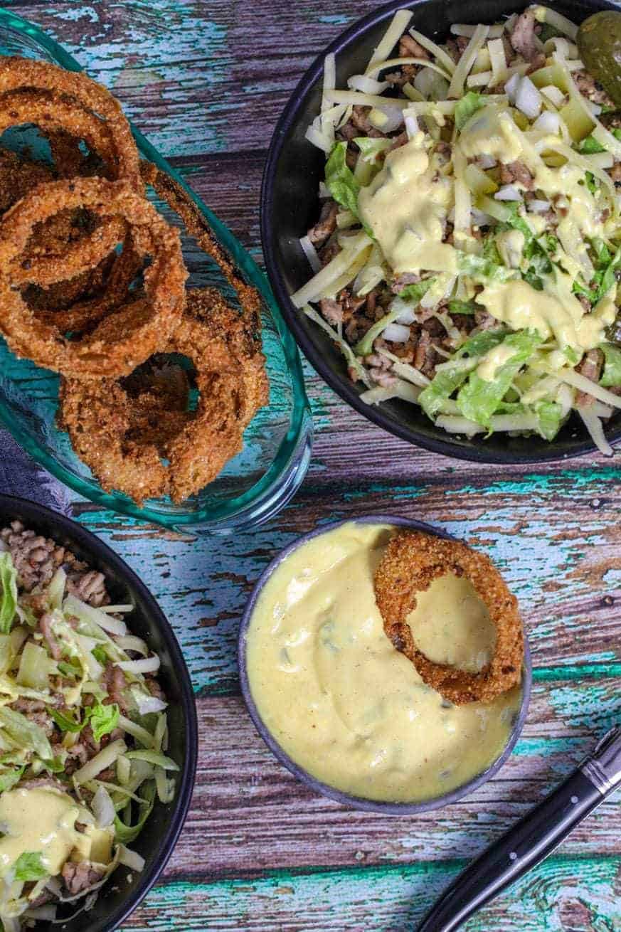 Keto rings with a burger bowl and dressing on a wood backdrop.