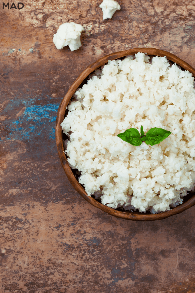 Cauliflower rice in a wood bowl on a brown background