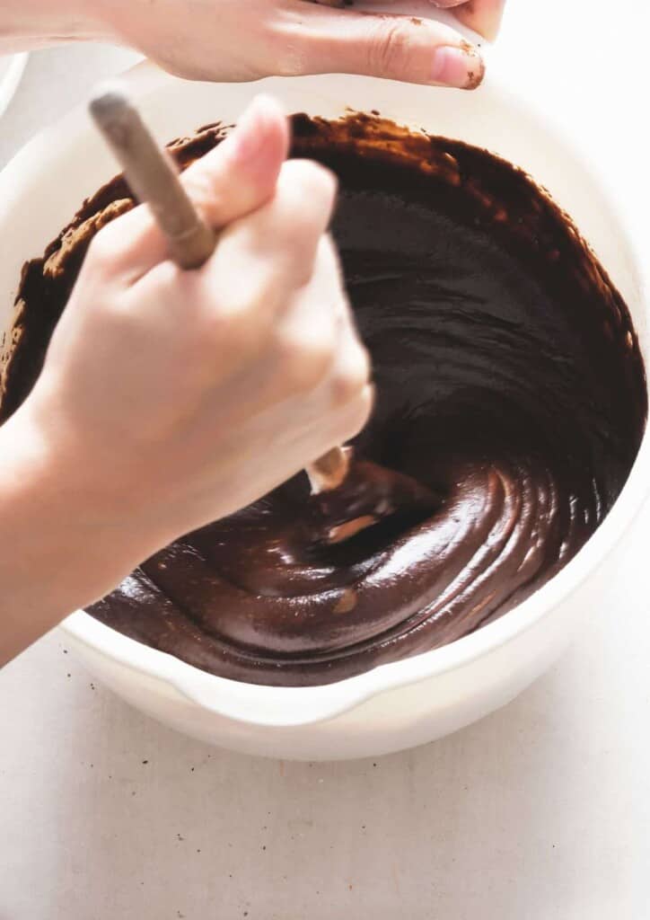 brownie batter being mixed in a white bowl