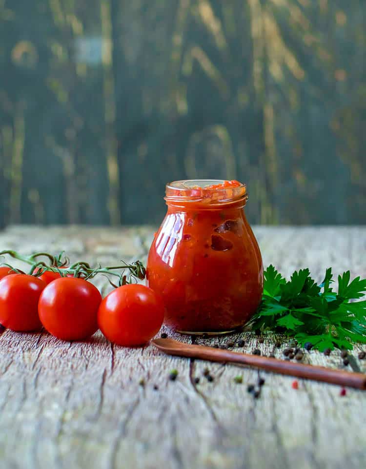 Keto Marinara Pizza Sauce in a jar with tomatoes and parsley