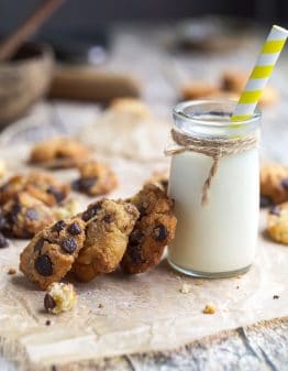 glass of milk with 3 cookies leaning on it