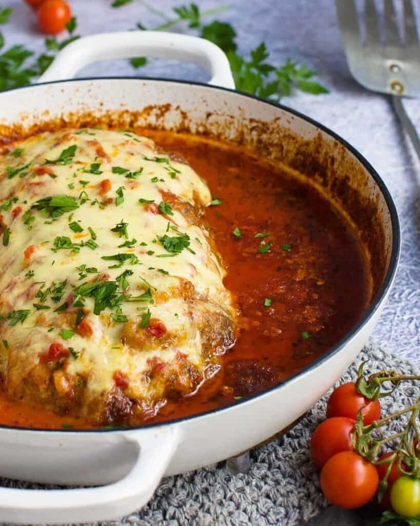 Full meatloaf in a pan with tomato sauce and parsley sprinkled over