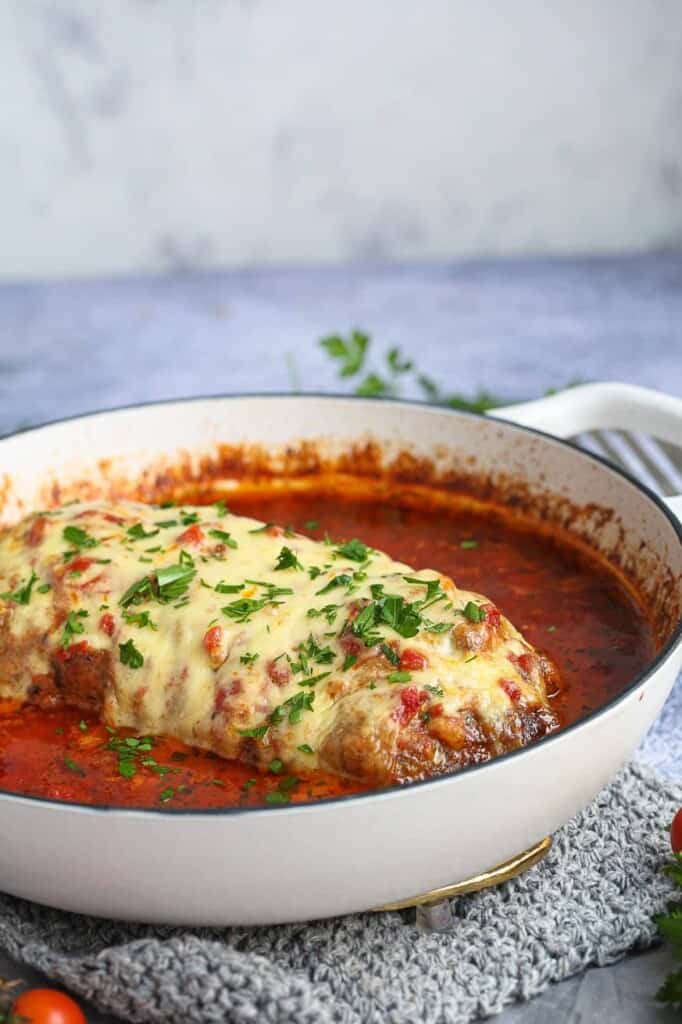 Full meatloaf in a pan with tomato sauce and parsley sprinkled over