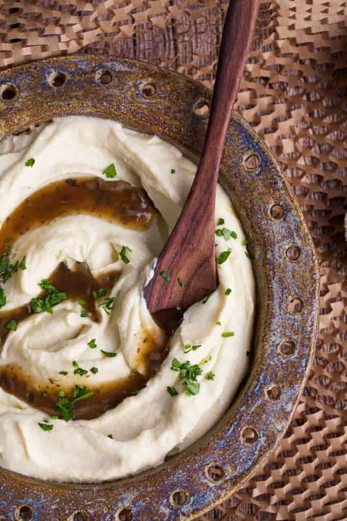 cauliflower mash and gravy in a bowl with spoon