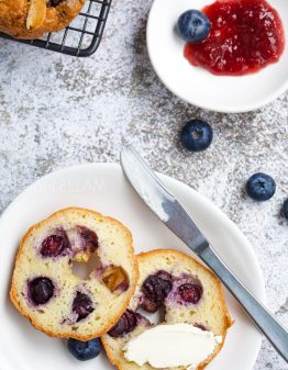 keto blueberry bagels on a white plate with extra berries and jam