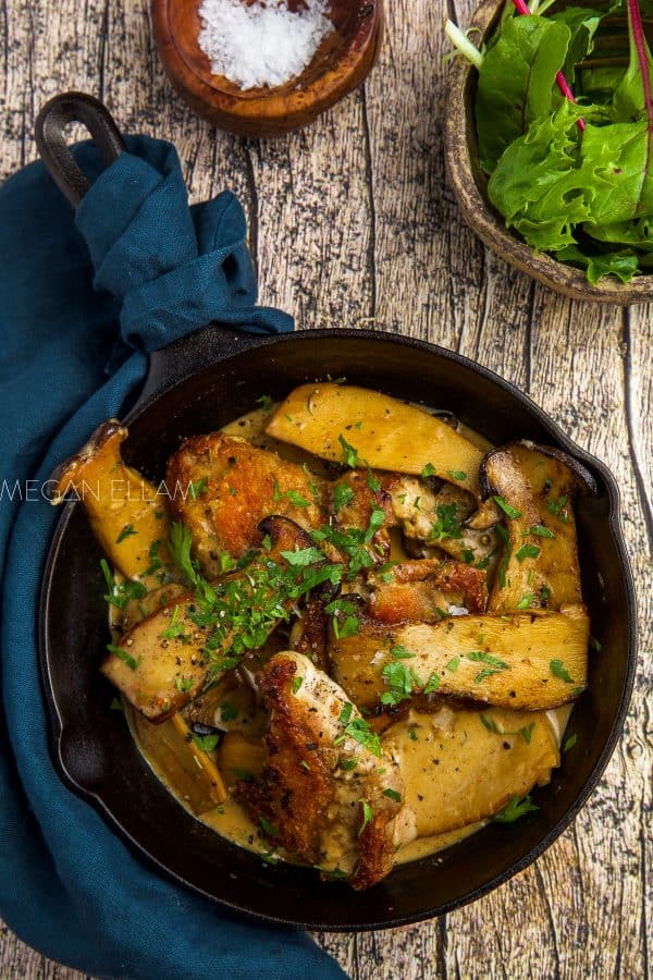 cast-iron pan with creamy mushrooms and chicken in it.