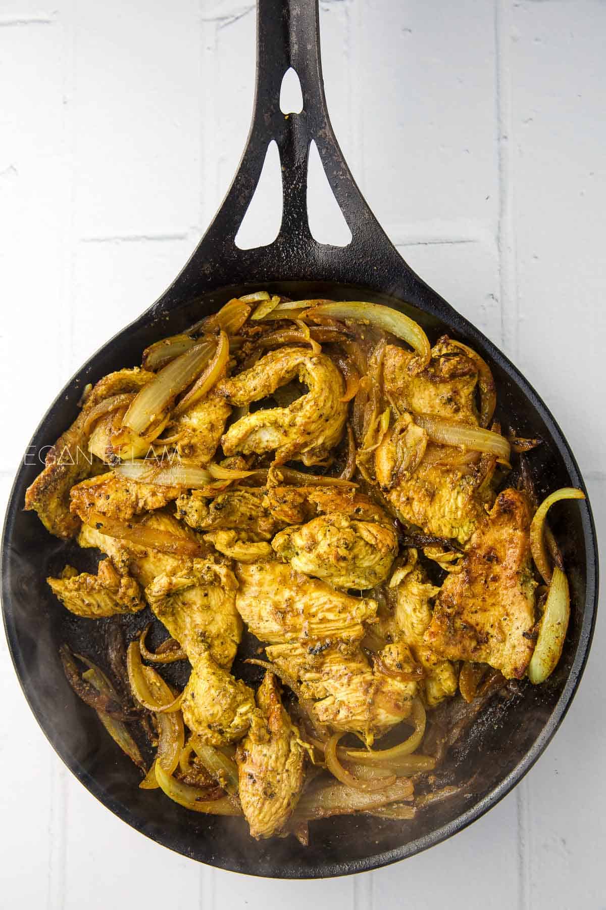 Chicken and onions in a cast iron pan.