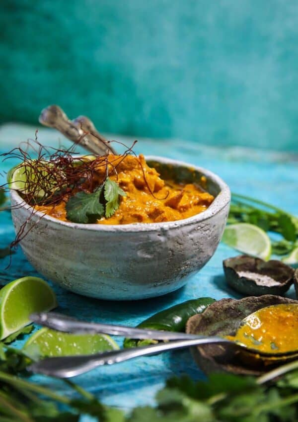 Bowl of curry in a green background.