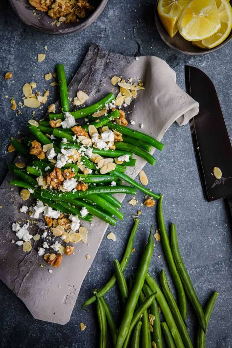 Air Fryer Green Beans with feta and olives on a grey piece of pottery.