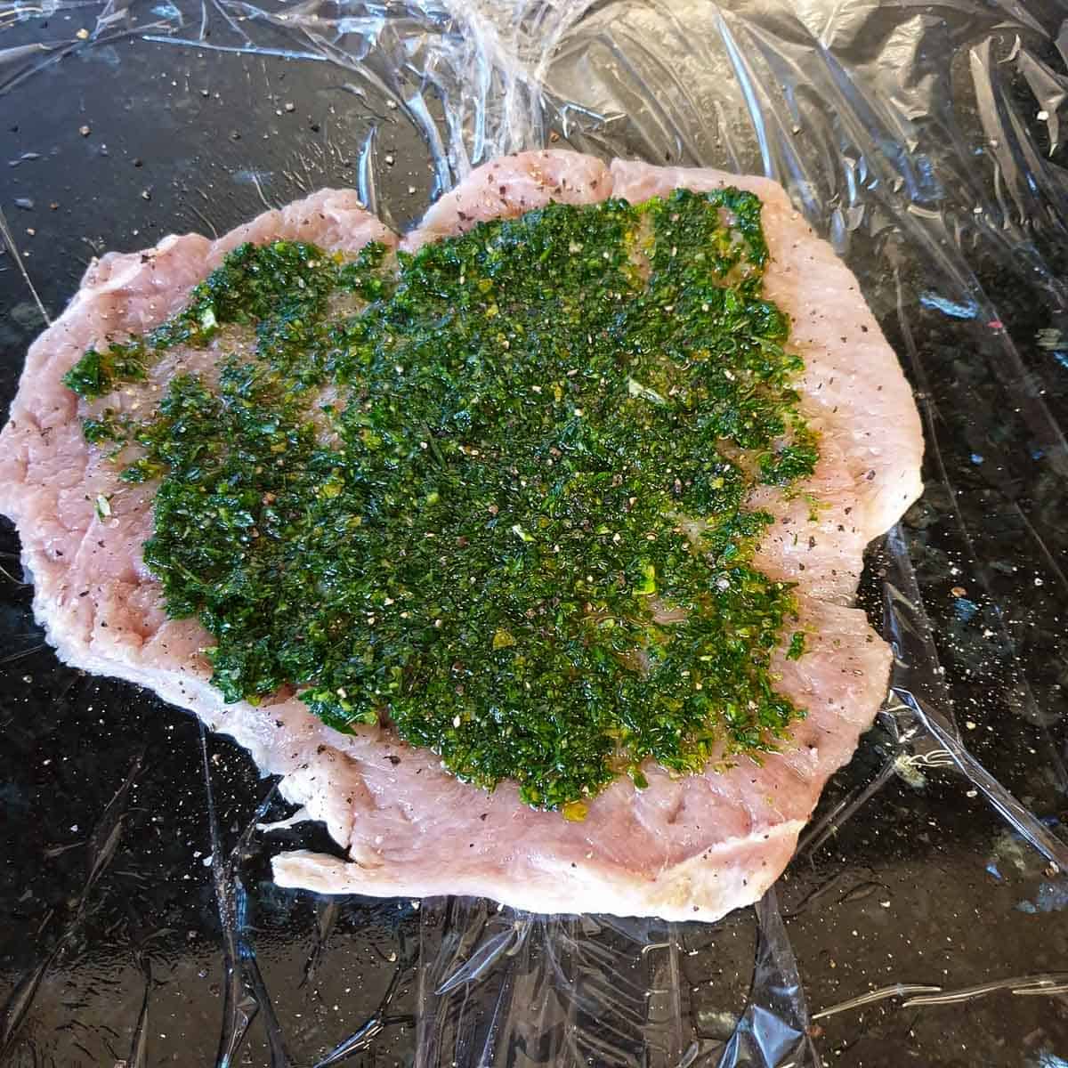 A flattened turkey breast with a herbed paste spread over it.