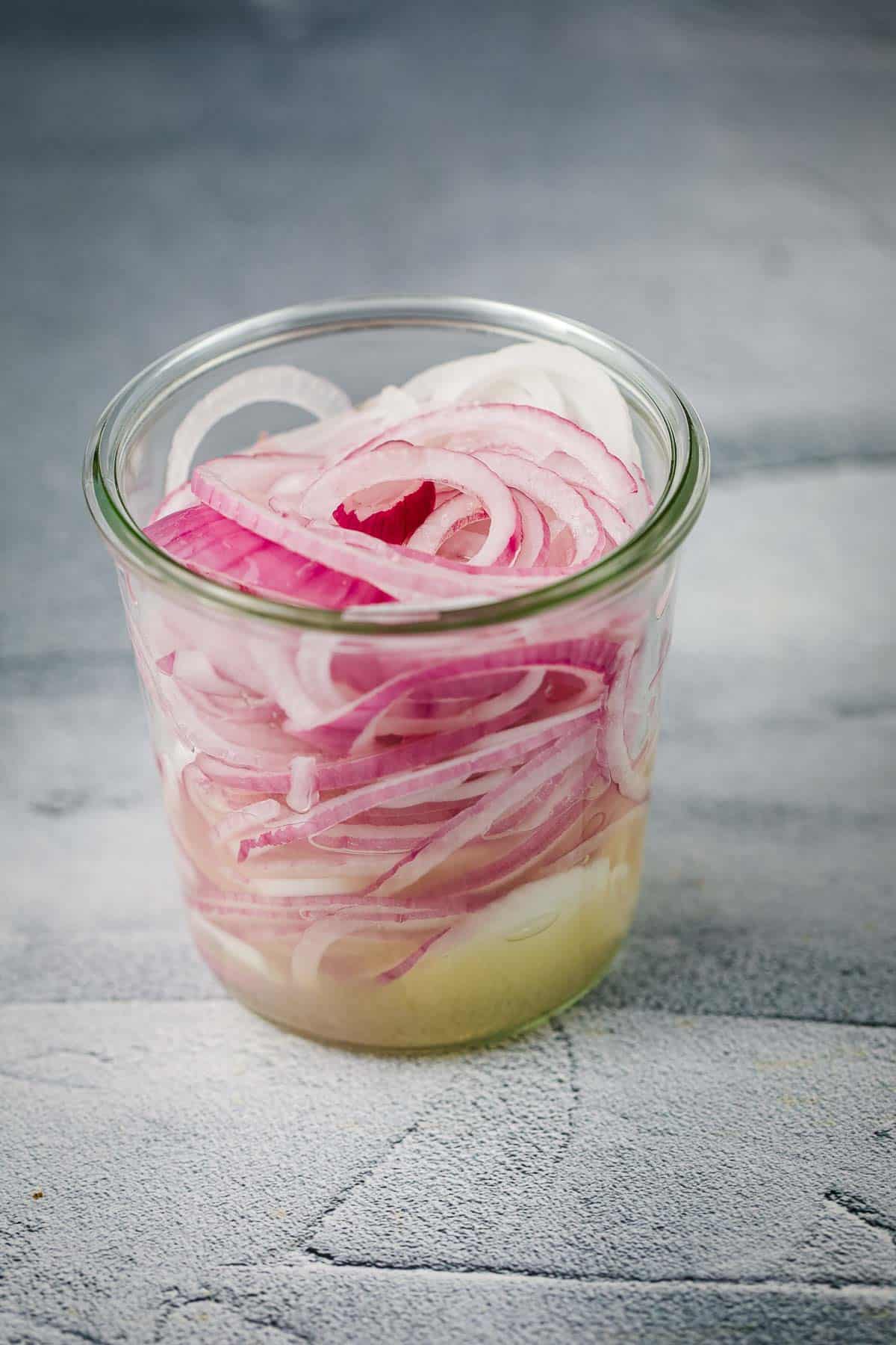 Red onion, lime juice and salt in a jar.