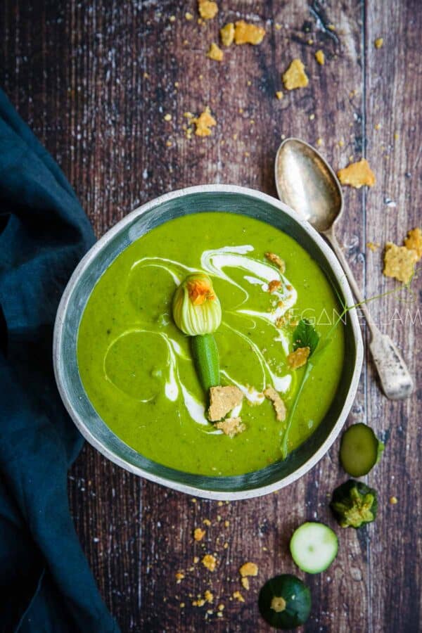 A bowl of zucchini soup om a brown backdrop.