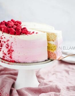 A pink ombre keto cake with a slice slightly pulled out on the cake stand.