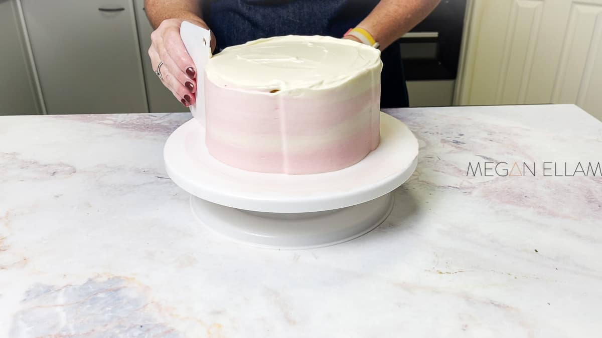Scraping frosting from an ombre cake.
