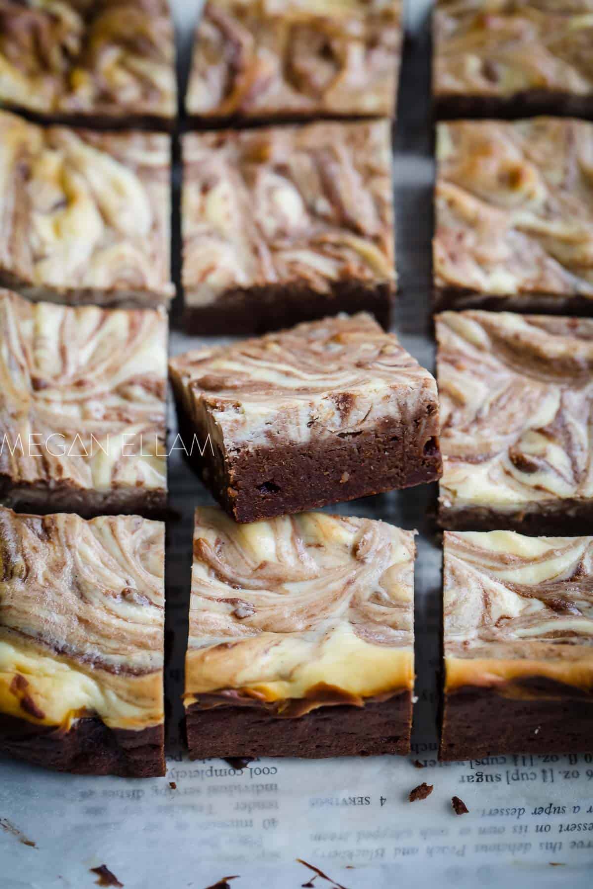 12 cheesecake brownies on baking paper but with one angled up to show you how moist and fudgy it is.