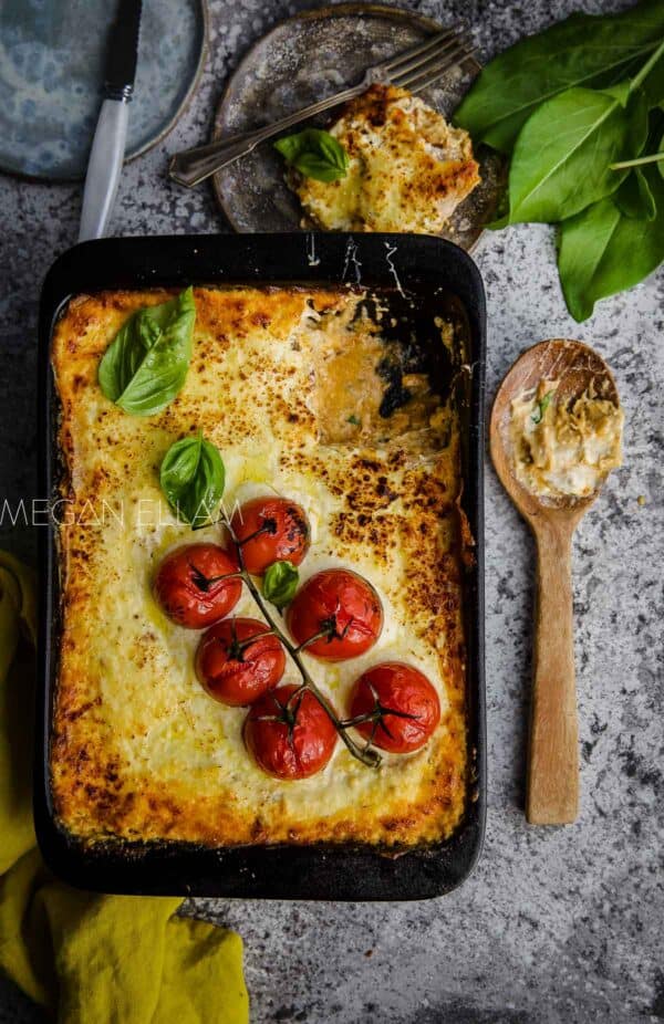 a lasagna in a black dish with truss tomatoes on top.
