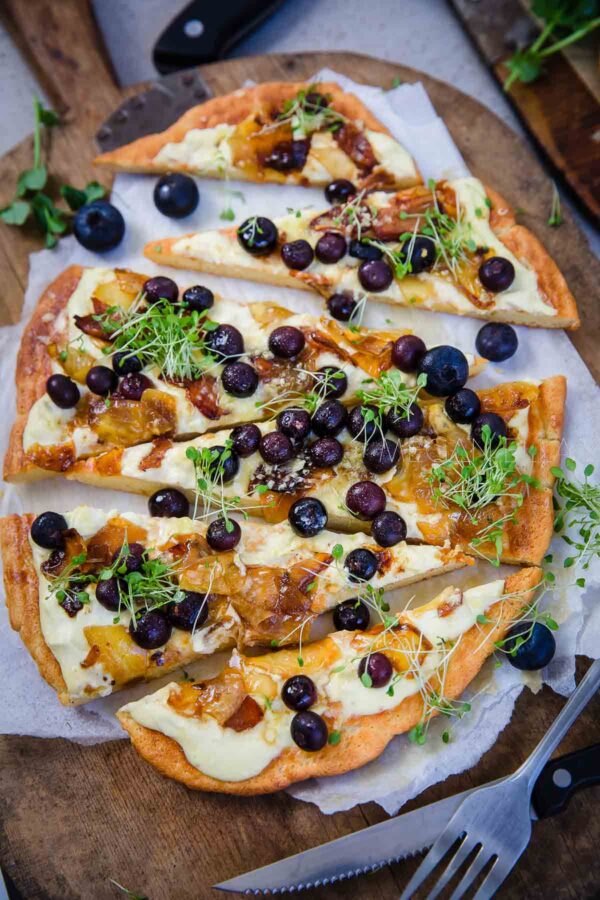 A blueberry and cremem fraiche pizza on a cutting board.