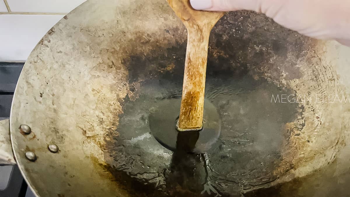 A wooden spoon handle in hot oil in a wok.