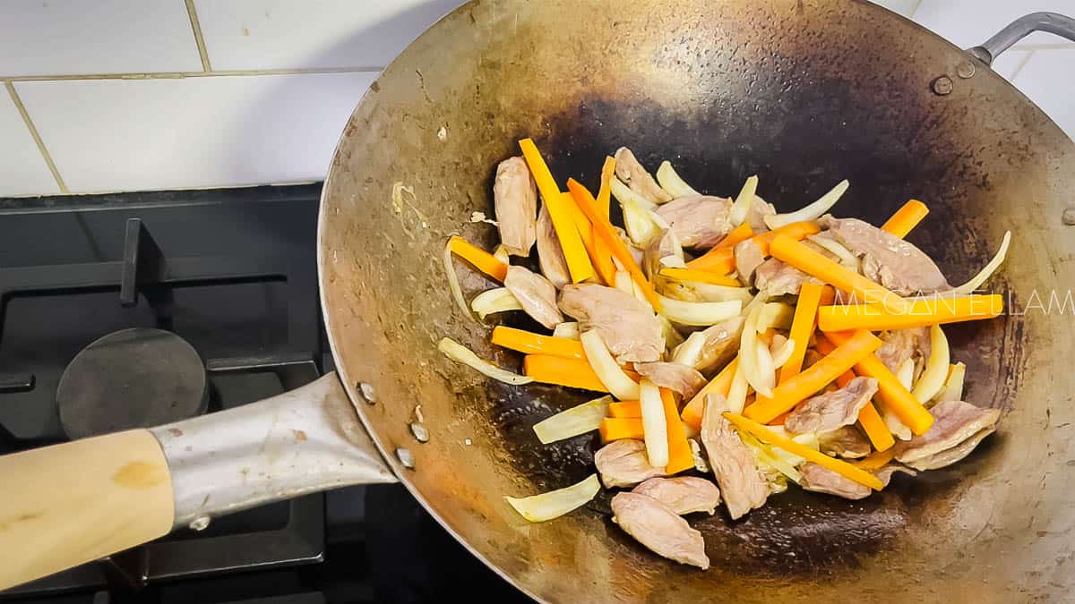 Duck, carrot and onions in a hot wok.
