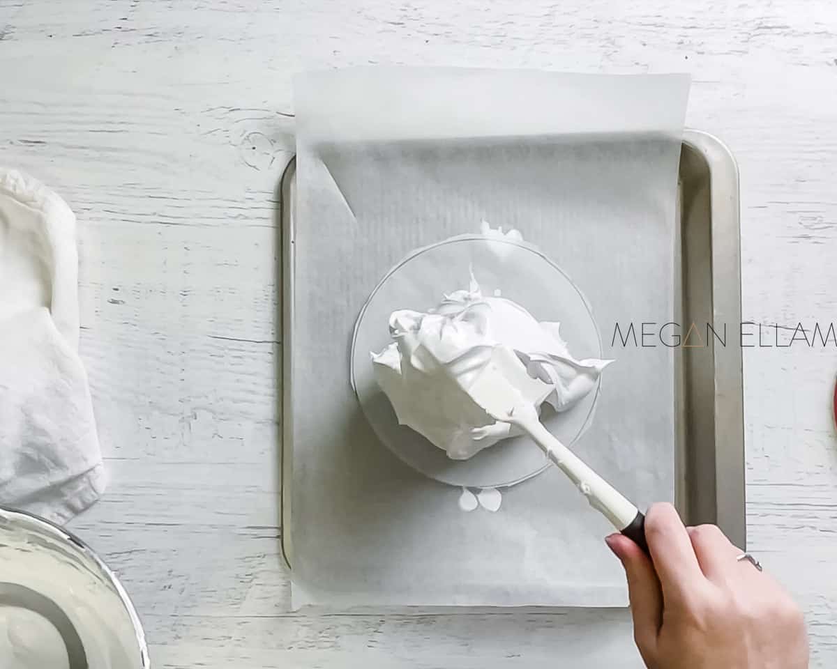 A white spatula dolloping meringue onto a baking tray.