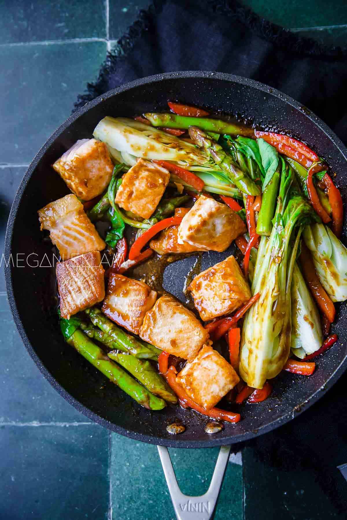 Salmon and vegetables in a frying pan.