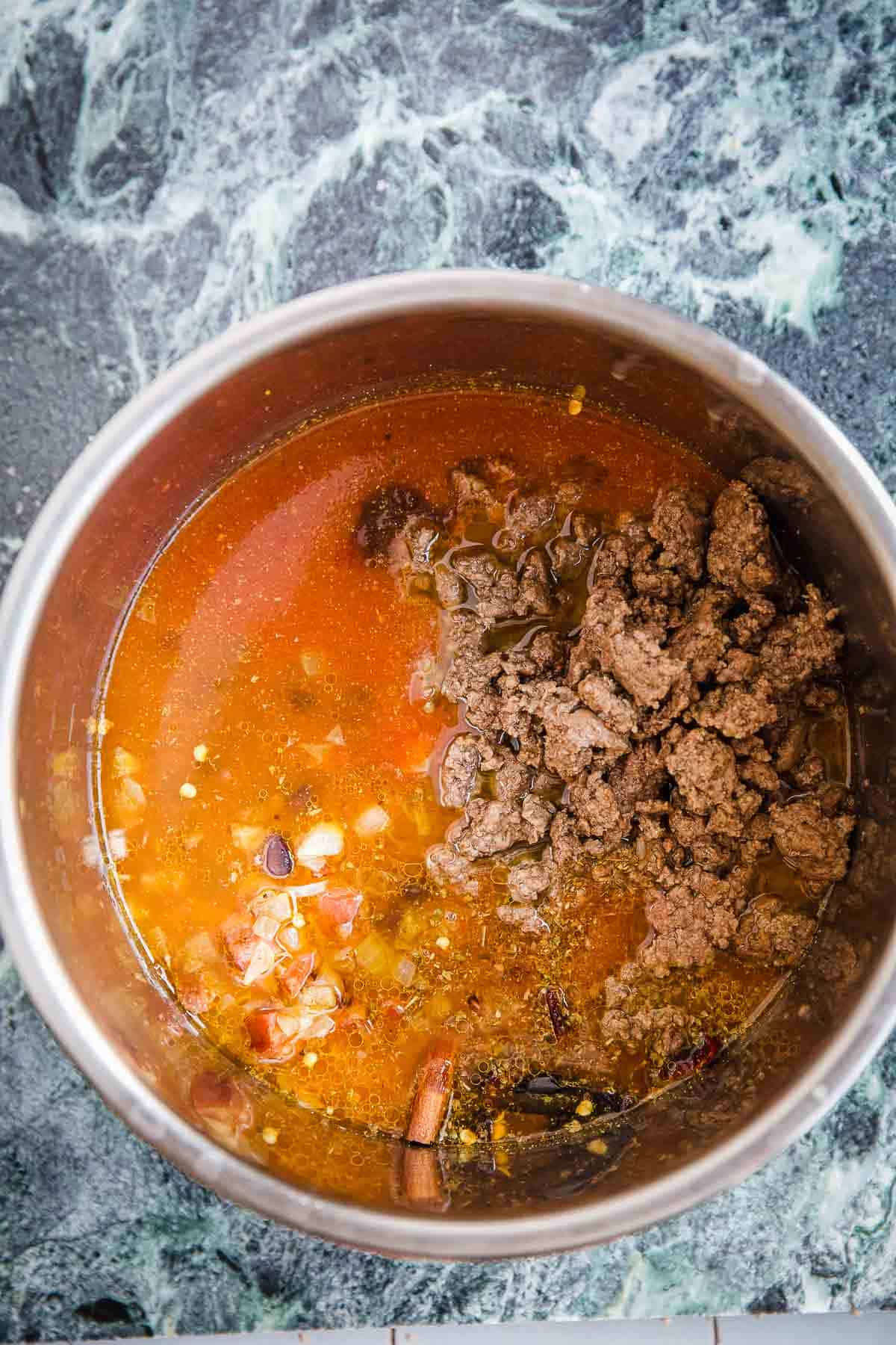 Browned meat and chili ingredients in an Instant Pot bowl.