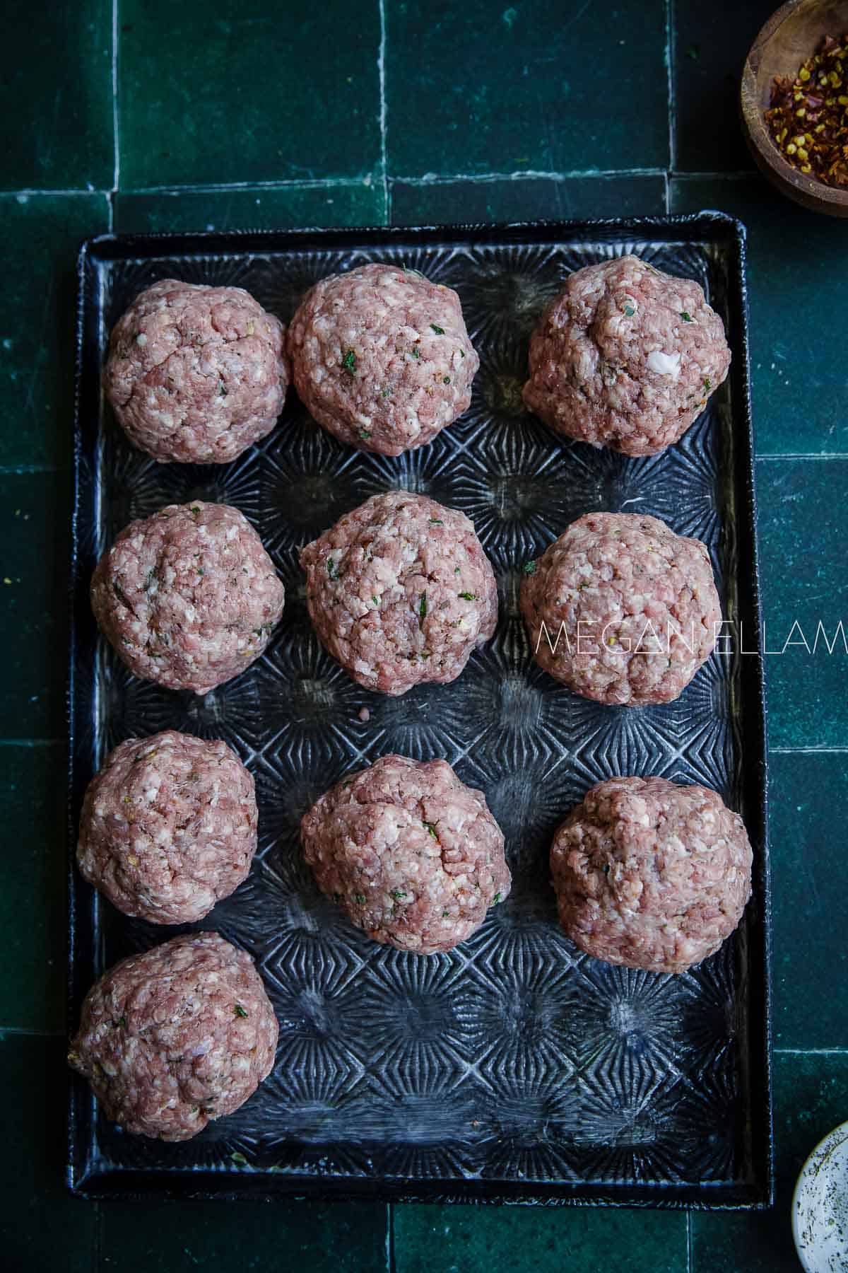 Meat balls on a large baking tray.