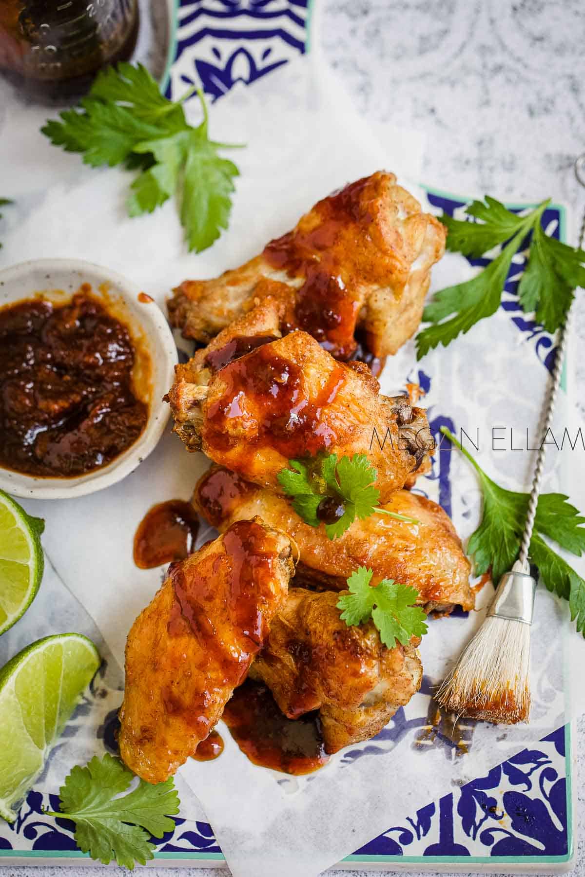 Keto Chicken Wings with a delicious Asian inspired sauce on baking paper with a glazing brush.