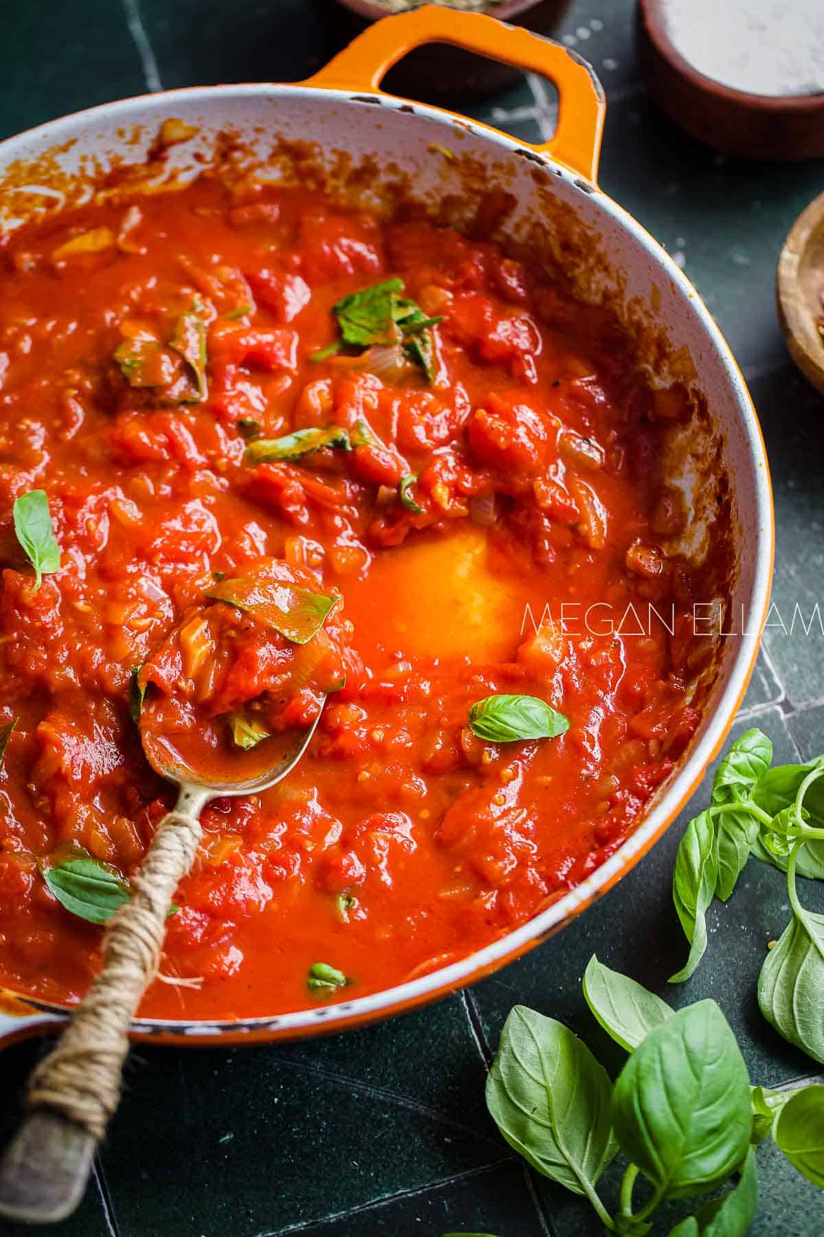 Italian tomato sauce in a skilley with a few basil leaves on top.