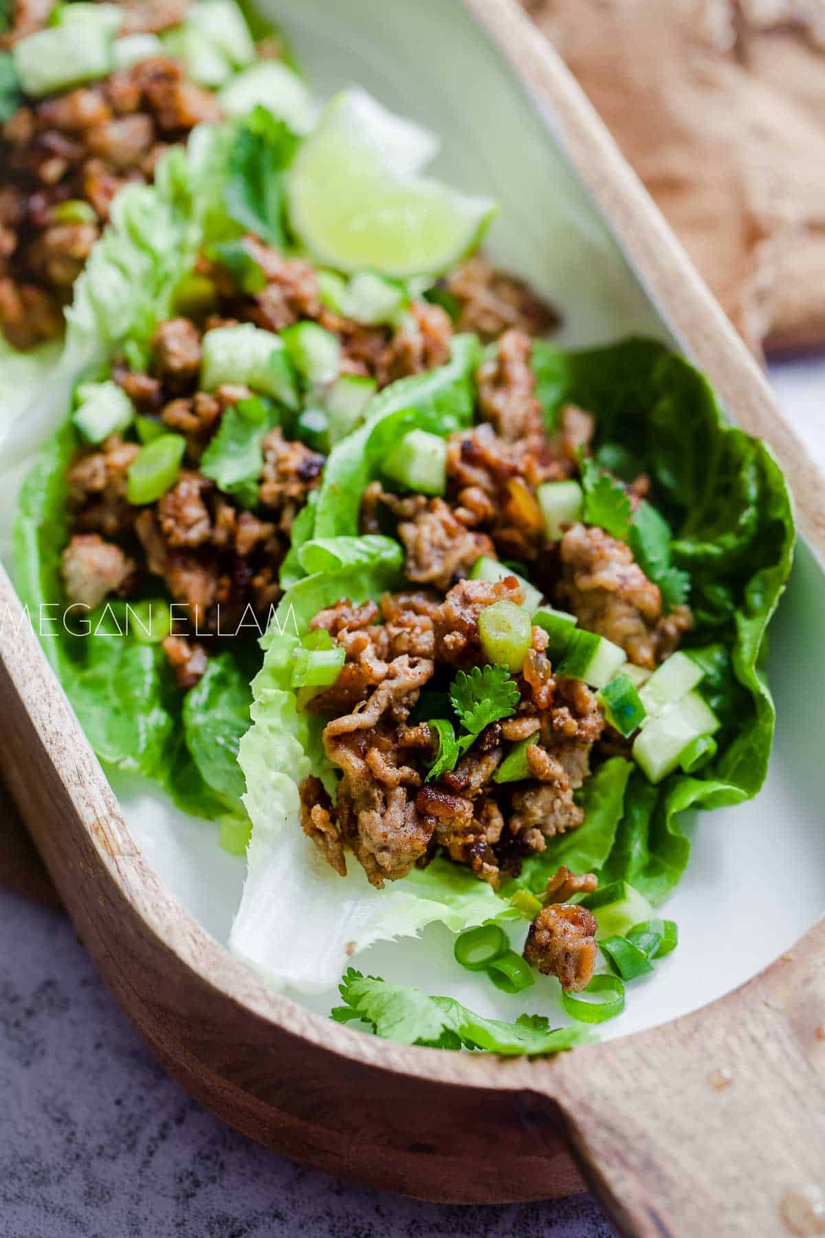 San Choy Bow in romaine lettuce cups in a white bowl.