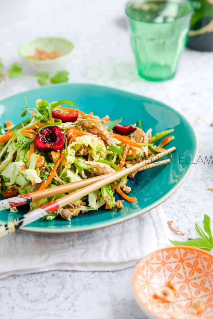 Asian Cabbage Salad on a green plate on a table with a green glass.