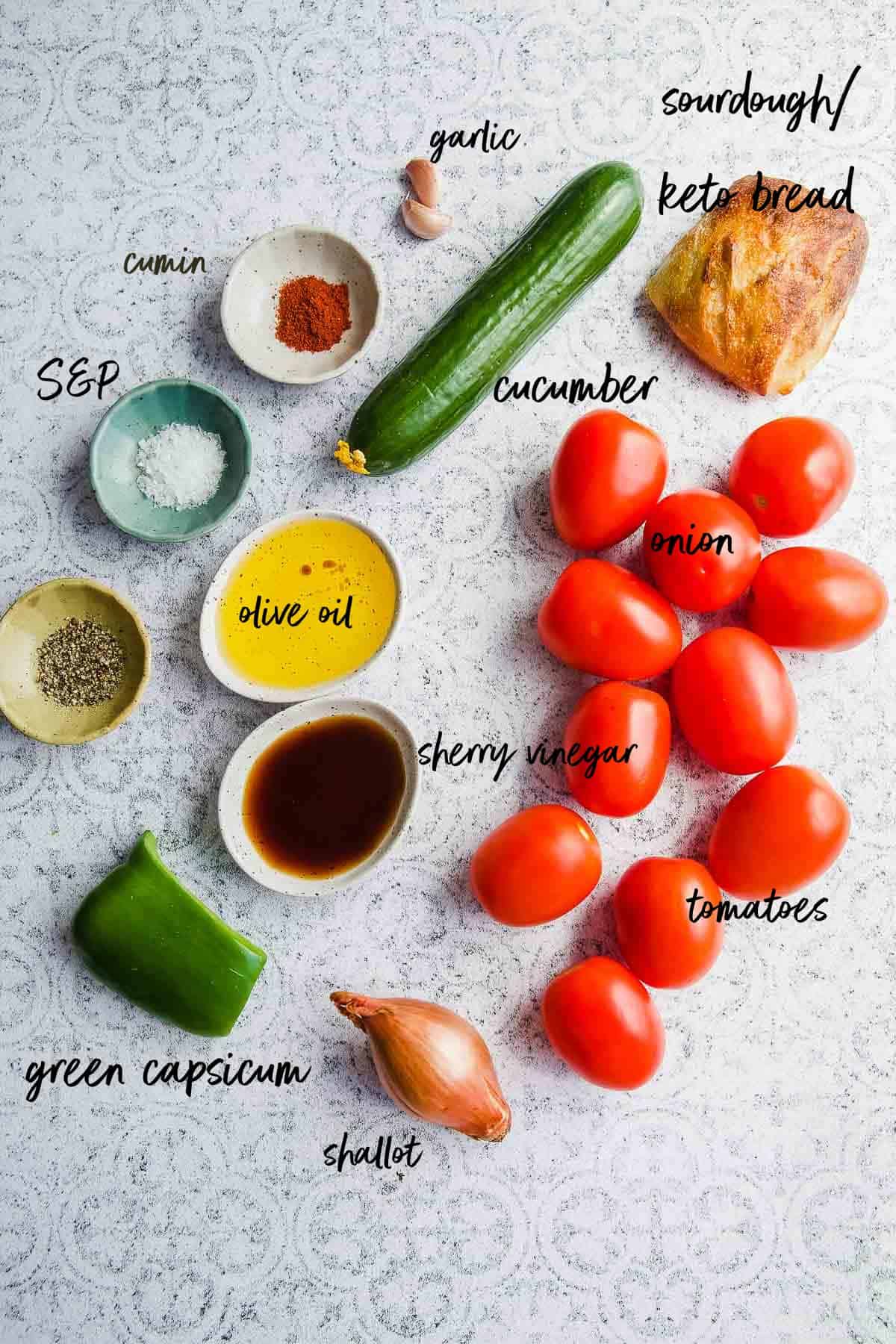Labelled gazpacho ingredients on a tiled backdrop.