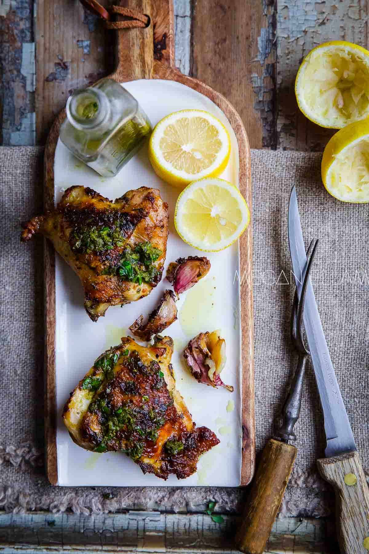 Grilled chicken coated with salmoriglio with lemons to the side.