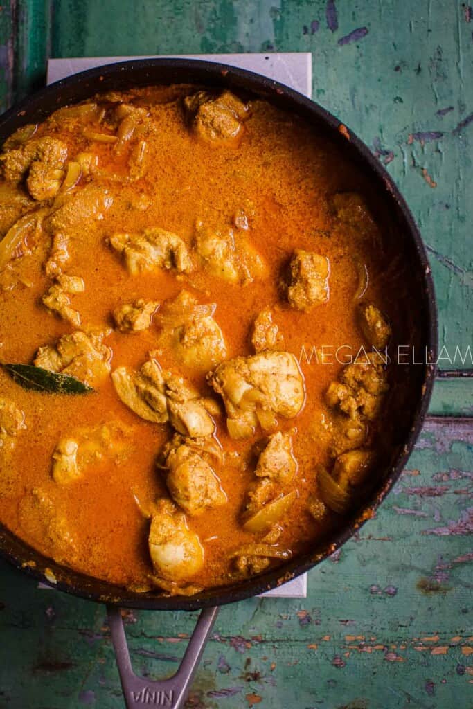 Chicken in a korma sauce in a skillet.
