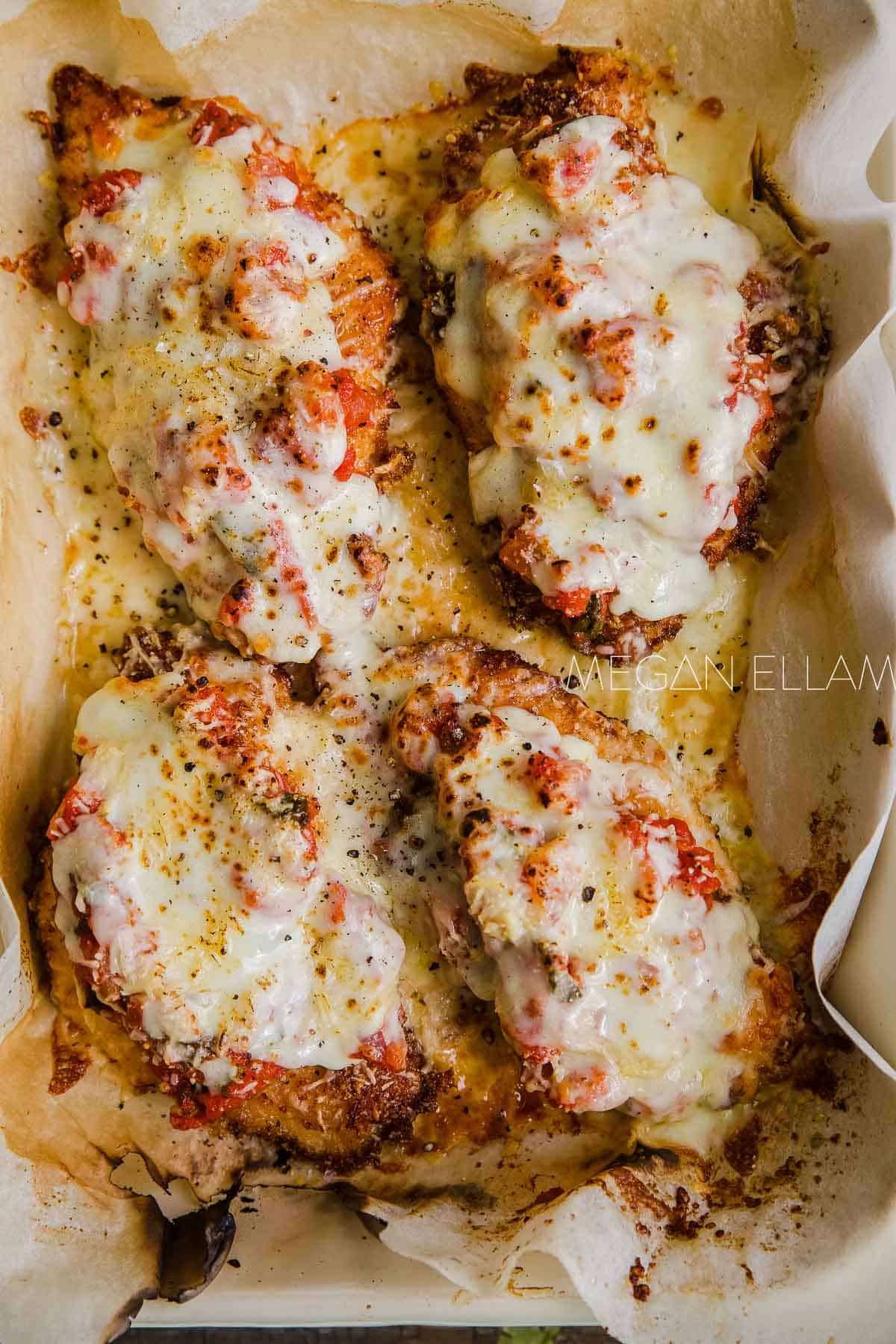 A close up of Keto chicken schnitzels smothered in Milanese sauce and melted cheese.