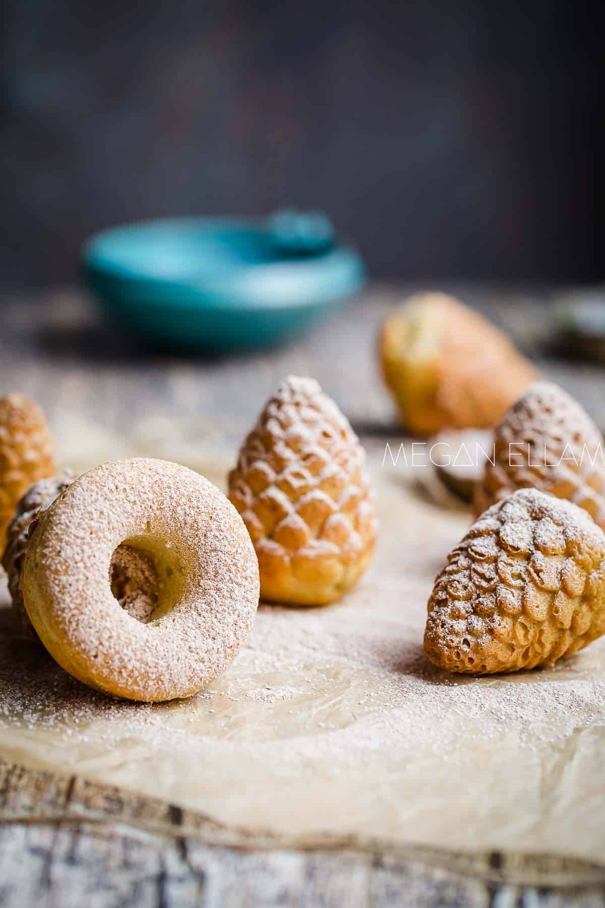Baked donuts in different shapes coated in powdered sweetener.