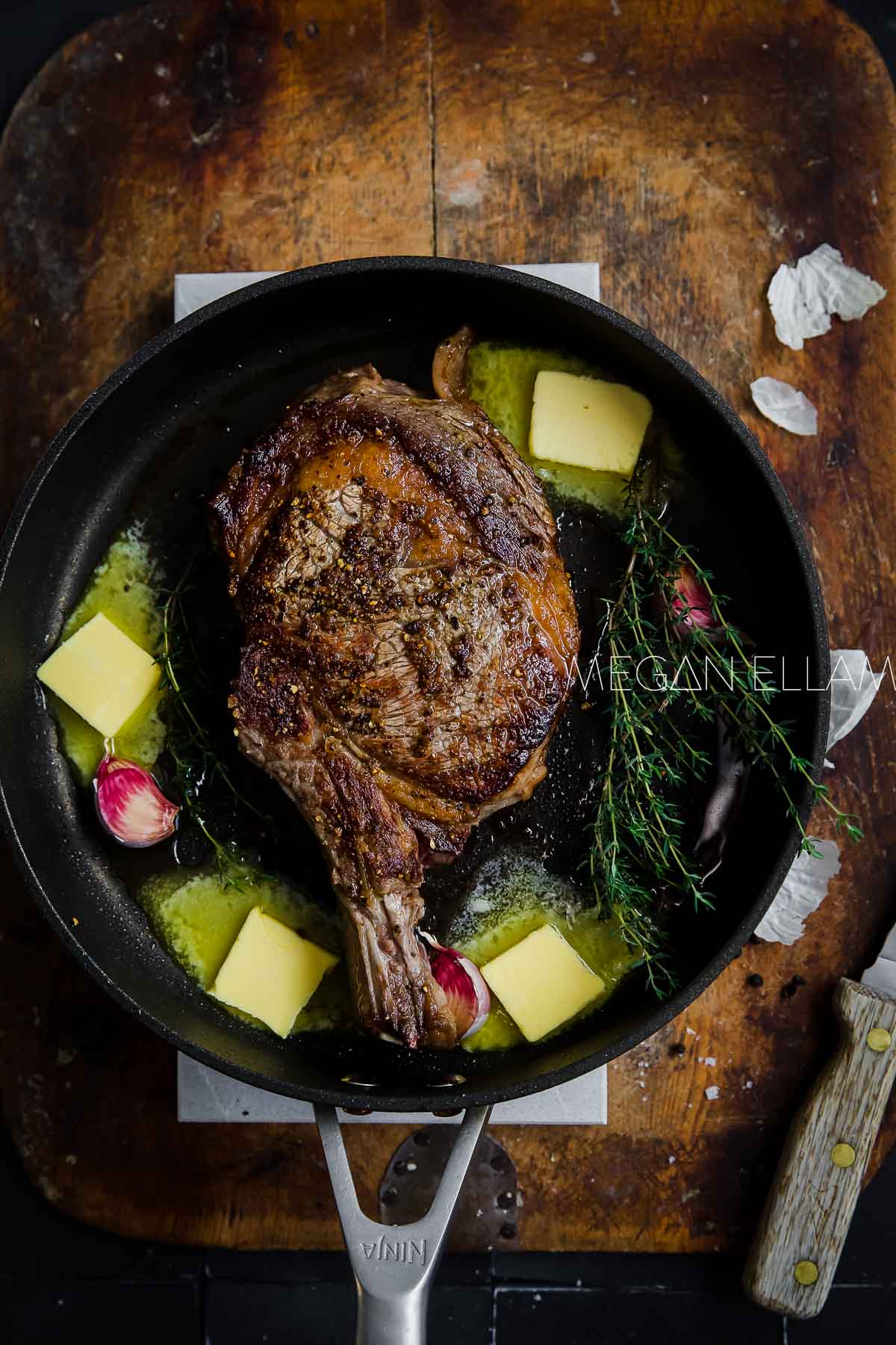 A cote beef rib in a cast iron pan with herbs, garlic and butter.