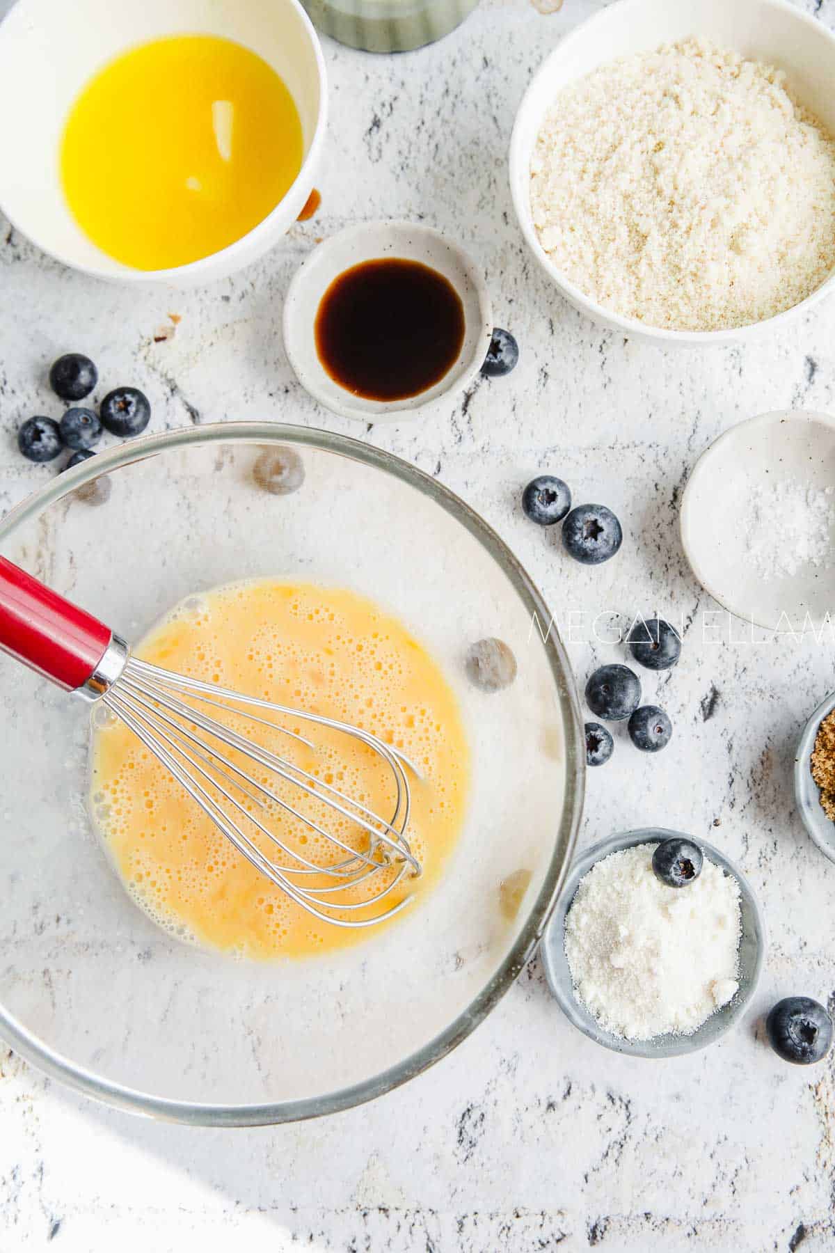 Whisked eggs in a bowl with keto pancake ingredients beside it.