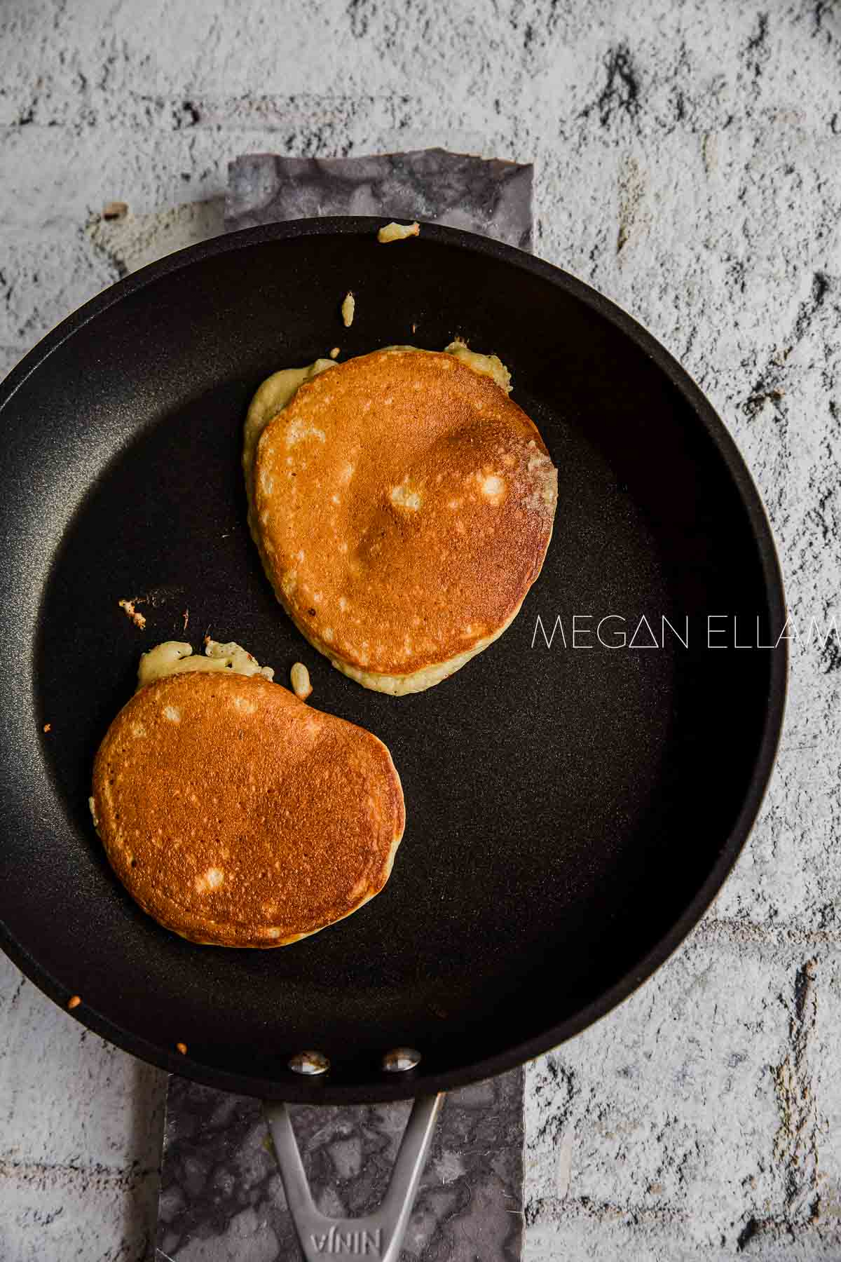 Two flipped low carb pancakes in a skillet.