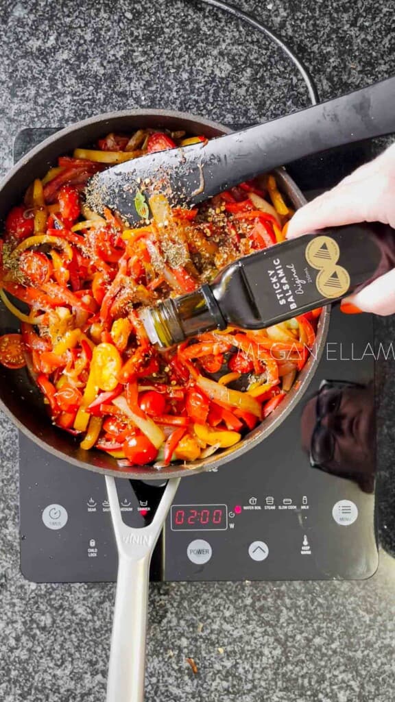 Pouring balsamic vinegar into sauteed peppers.