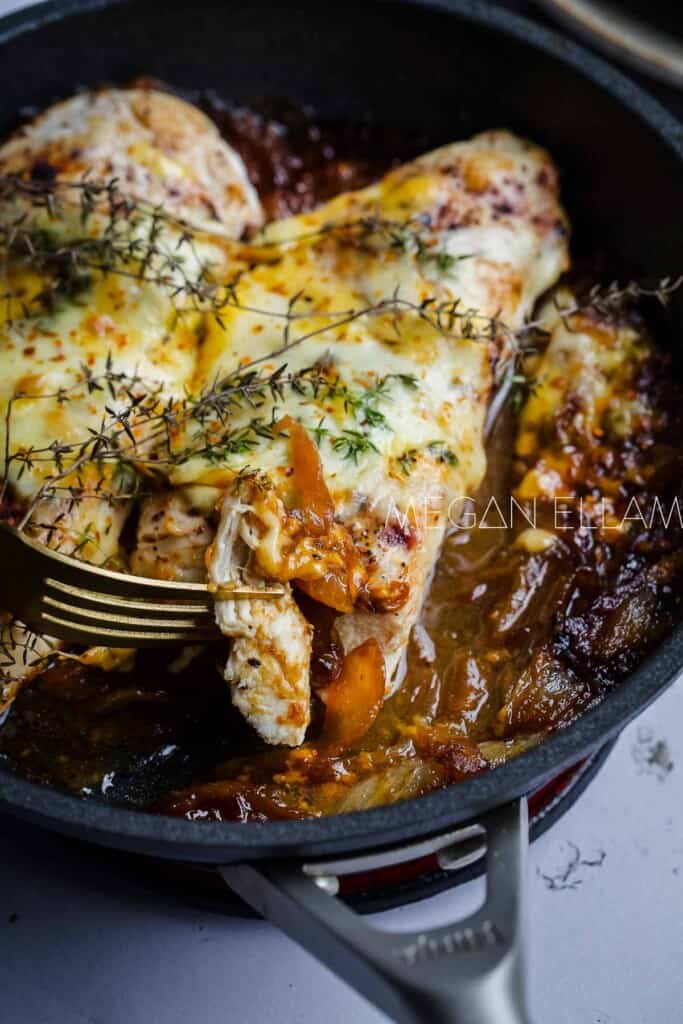 Chicken in onion gravy inside a cast iron skillet.